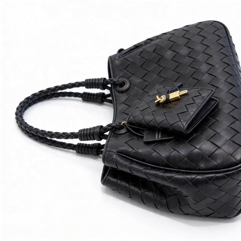 Bottega Veneta Andiamo Mini Tote in black, close-up of triangular mini pouch with gold padlock and brand tag