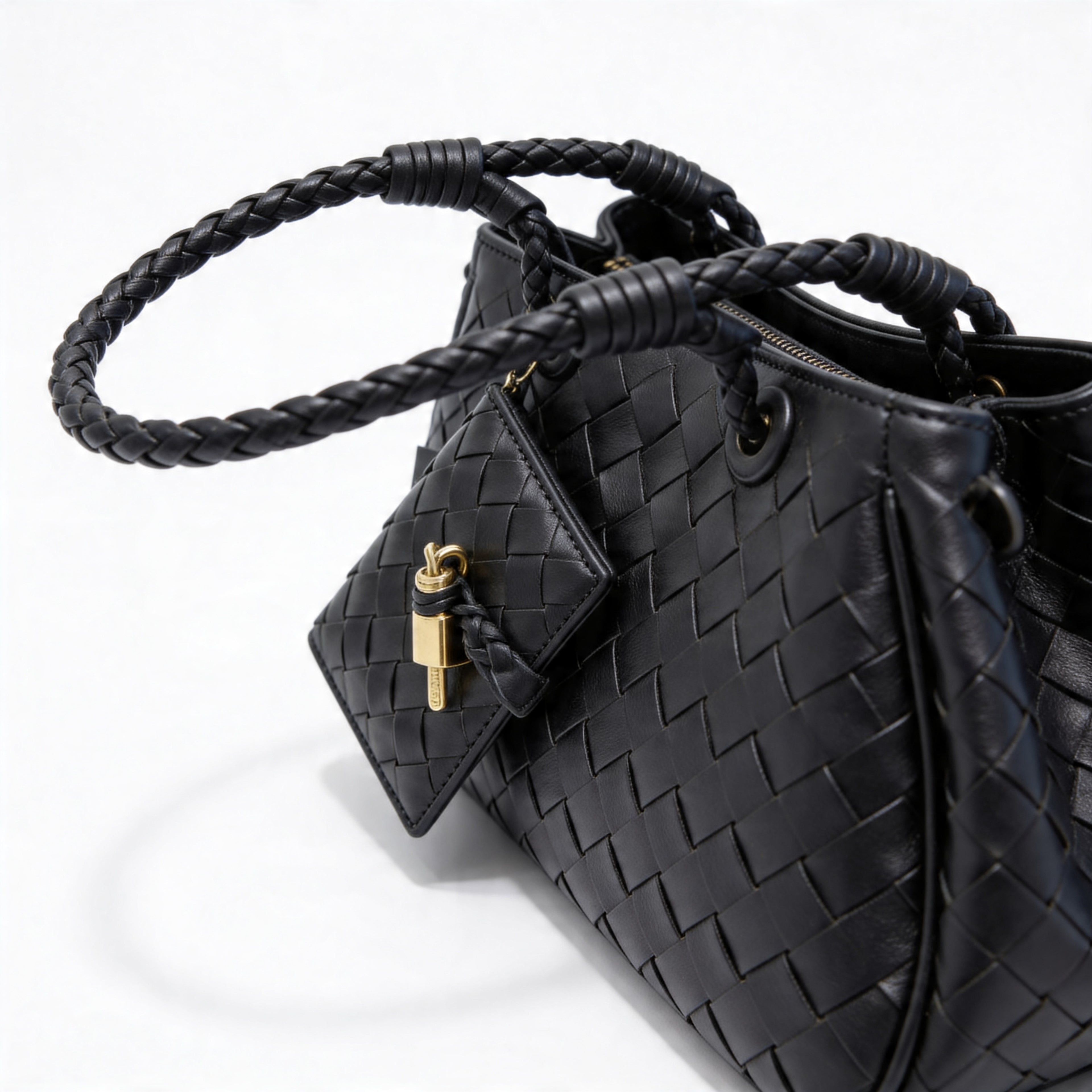 Bottega Veneta Andiamo Mini Tote in black, side close-up of braided handles and triangular charm