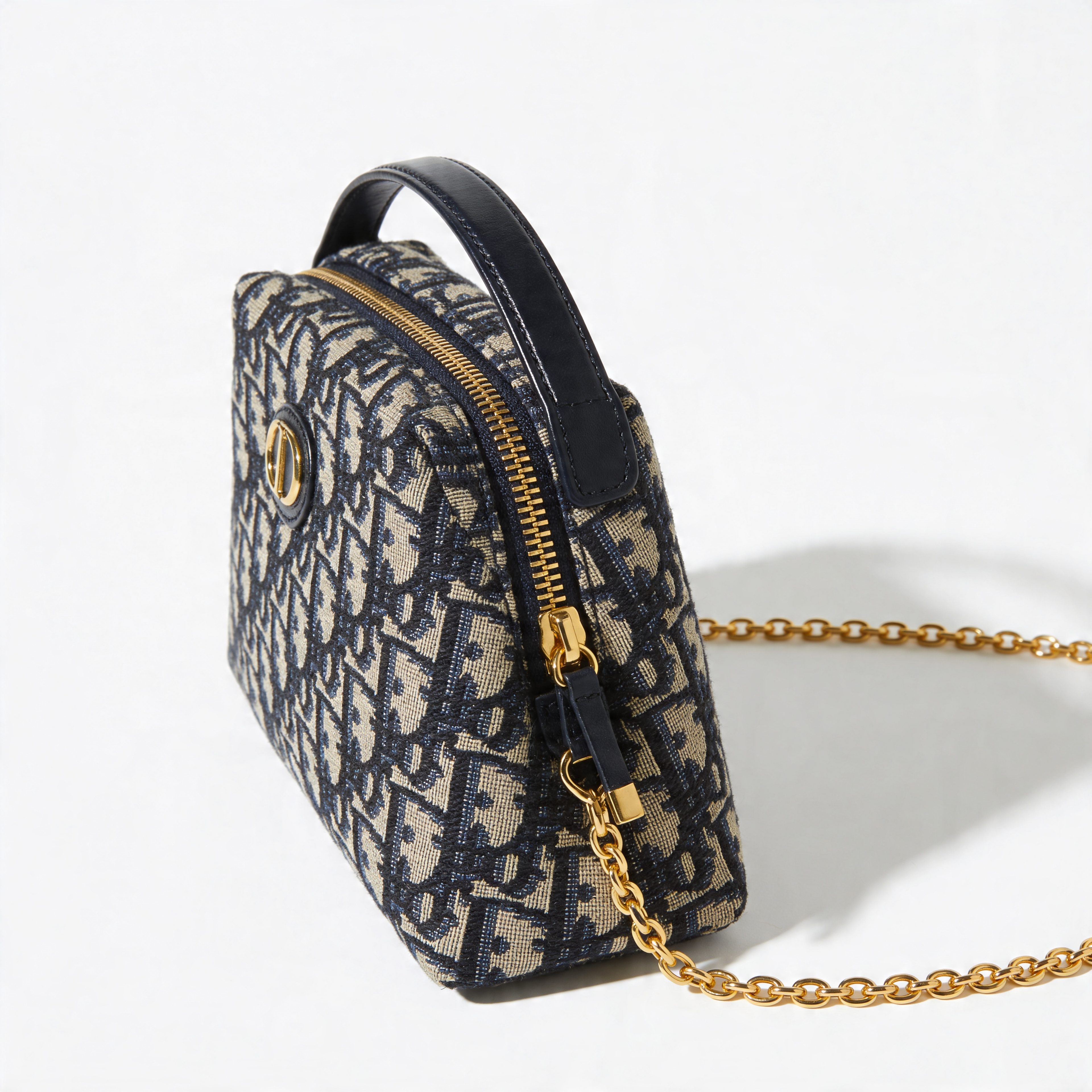 Christian Dior Bobby Bag, navy Oblique canvas, side profile with top handle, gold chain strap, off-white background